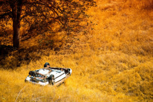 Rollover Compact Car Crash. White Crashed Car in the Mountain Road Ditch in California, USA. Traffic Accident.