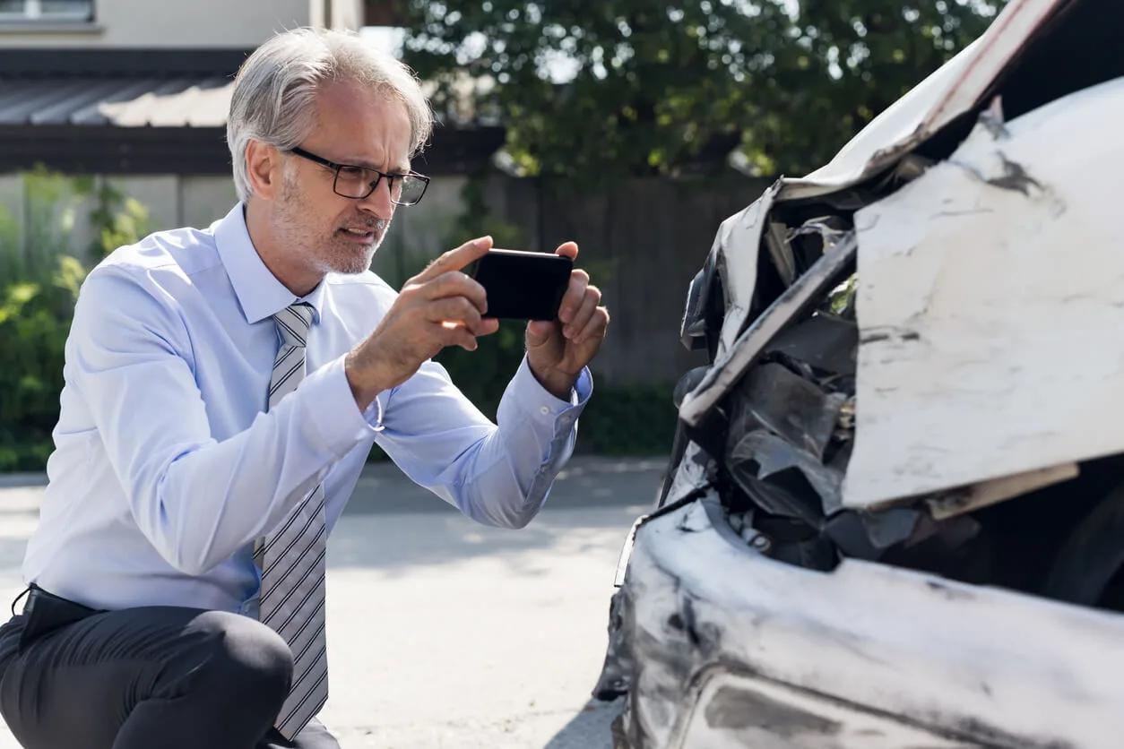 Man taking picture of damage done to car