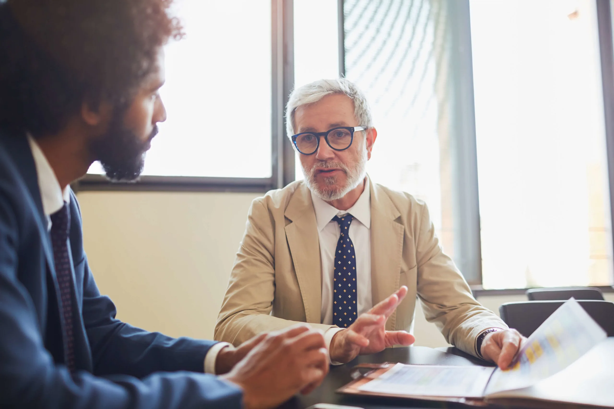 Attorney consulting a client across a desk in a bright office