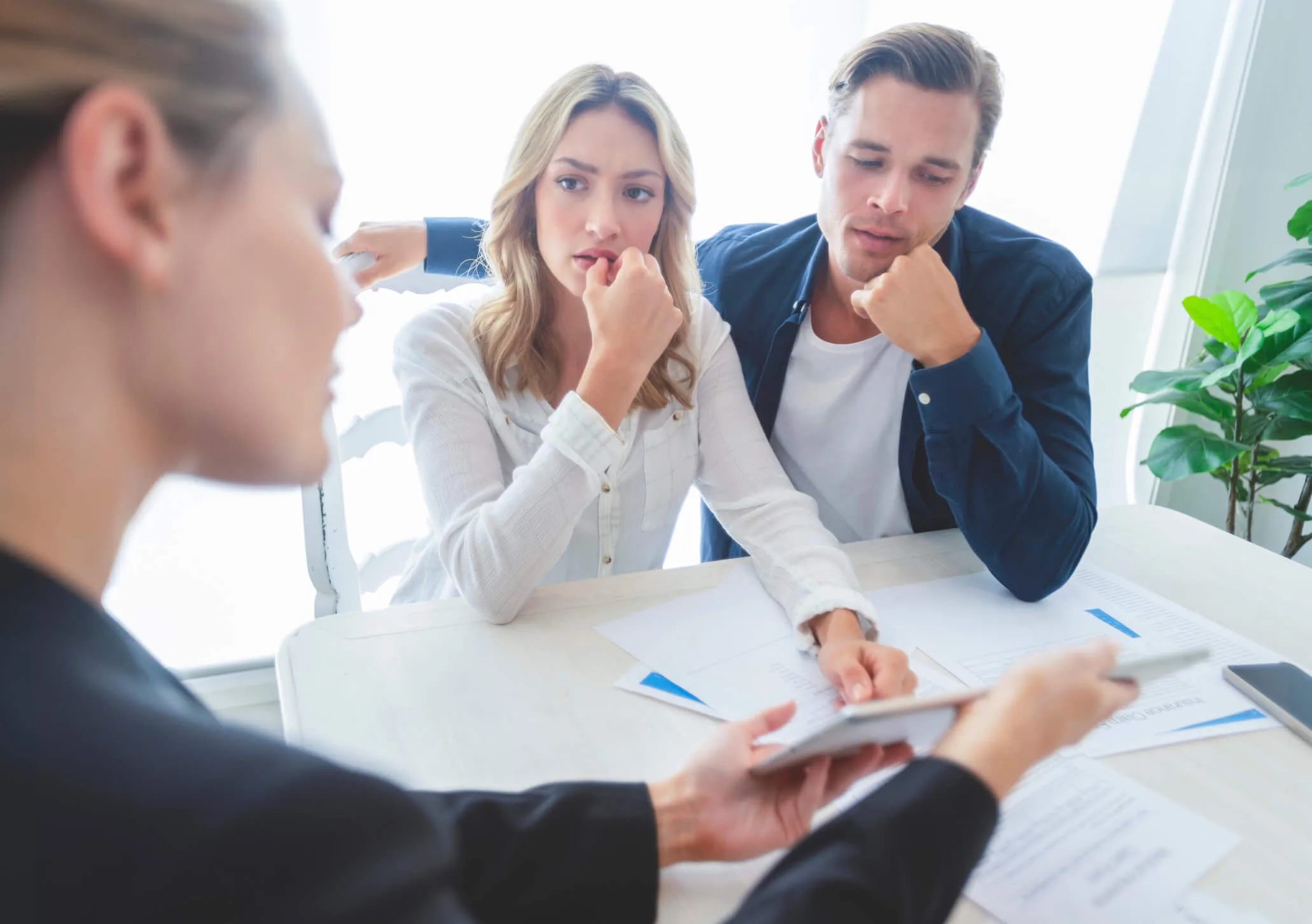 Worried couple meeting with advisor reviewing documents and tablet