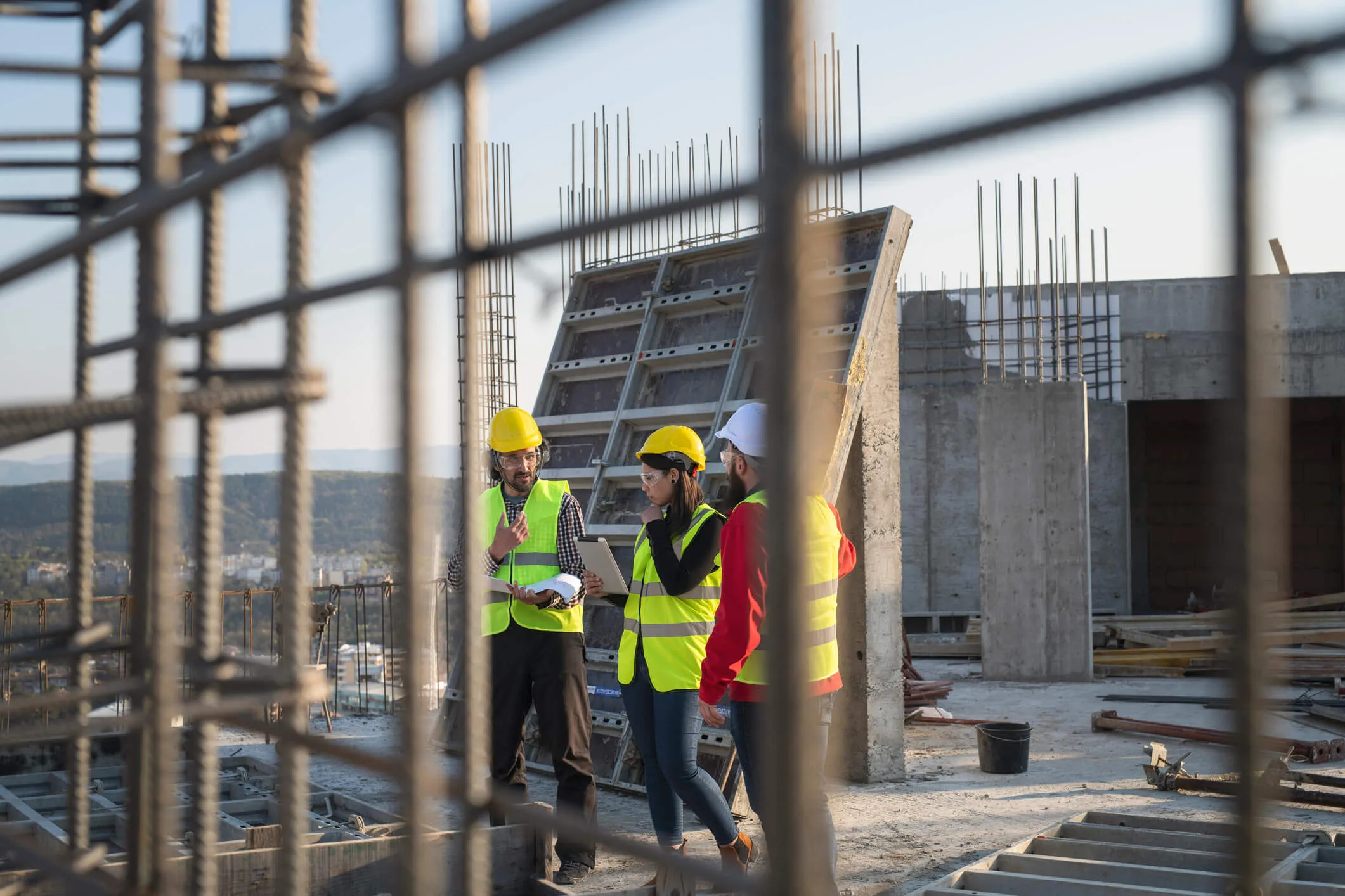 Construction managers in hard hats reviewing plans at reinforced concrete jobsite