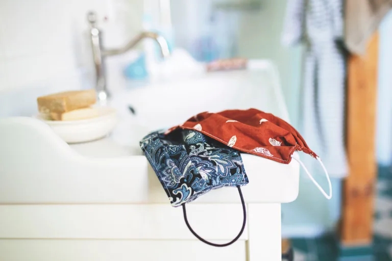 Reusable cloth face masks on bathroom sink edge