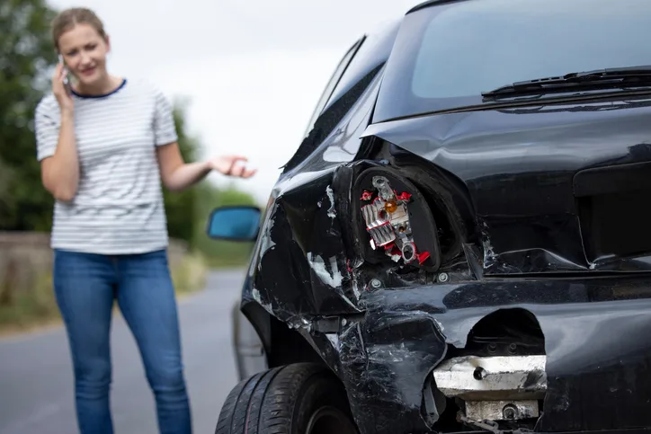 Woman calling next to damaged car