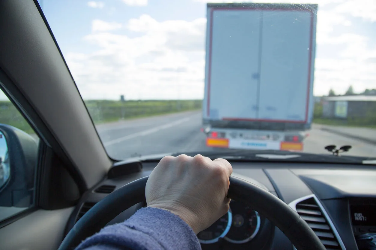 Driver’s view from inside a car following closely behind a large truck on a highway