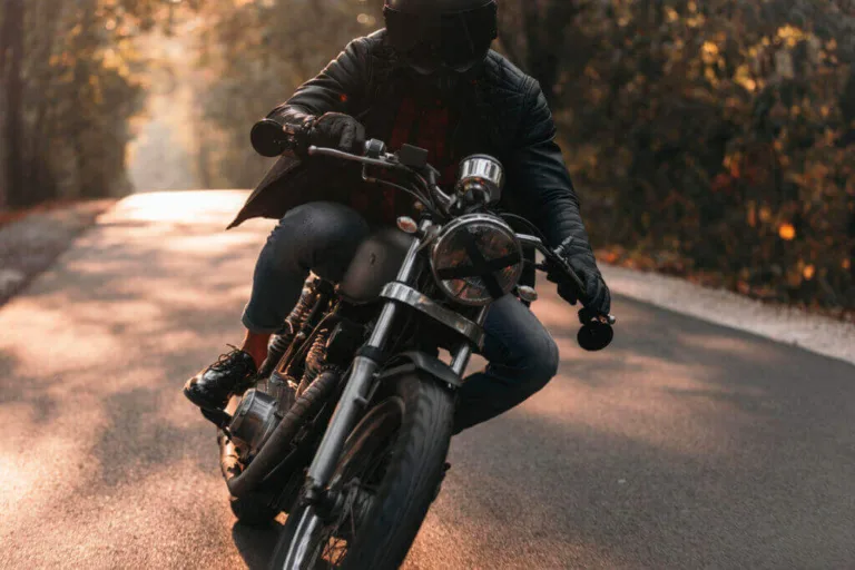 Motorcyclist leaning into a turn on a forest road.