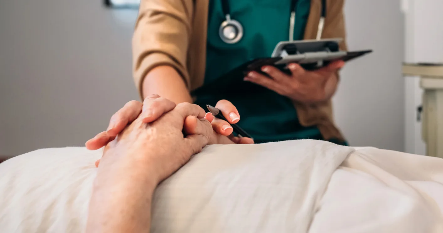 Compassionate bedside care—nurse holding elderly patient’s hand
