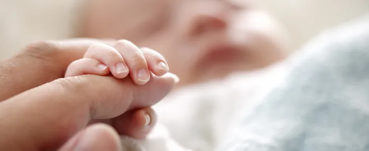 new born baby gripping on mothers hand episiotomy