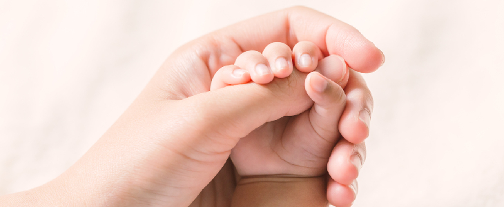 women holding baby's hand with hypoplastic left heart syndrome