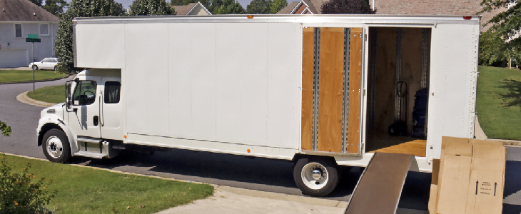 white moving truck parked in front of someone's yard