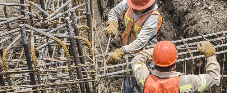 two construction workers handling a power tool