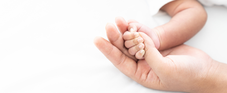 baby with spina bifida holding a person's hand