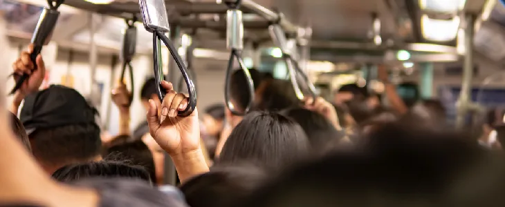 multiple passengers on a subway holding onto the railings