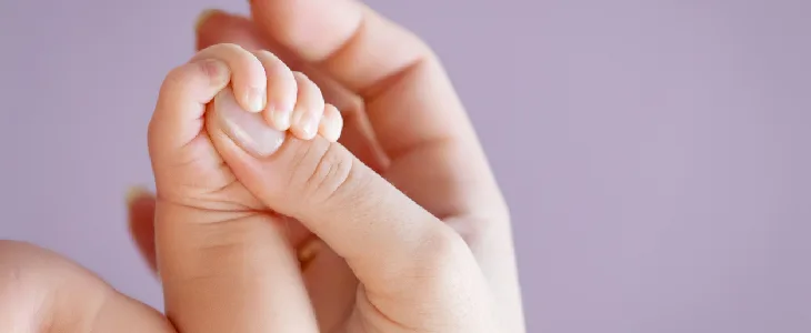 baby with tay sachs disease holding a person's hand