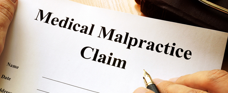 person filling out a medical malpractice claim form.