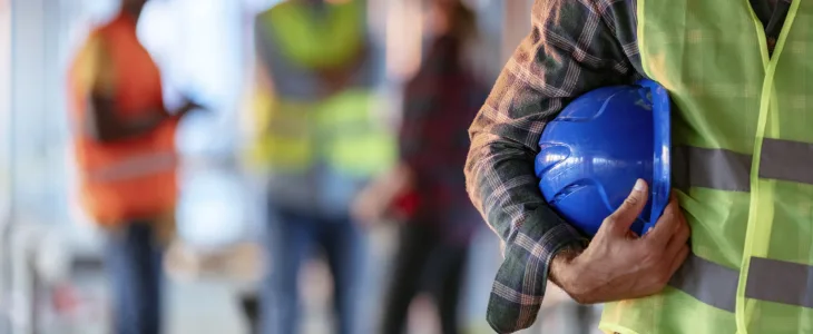 Construction worker clutching onto his helmet