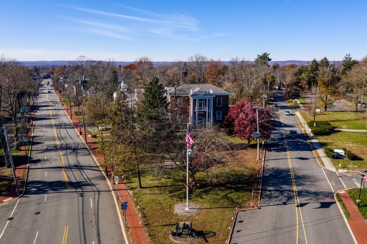 Quiet suburban intersection with a colonial-style building and fall foliage